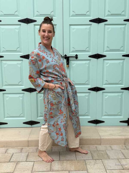 woman is wearing a blue waffle cotton bathrobe with vibrant floral print, posing in front of a pastel green paneled door