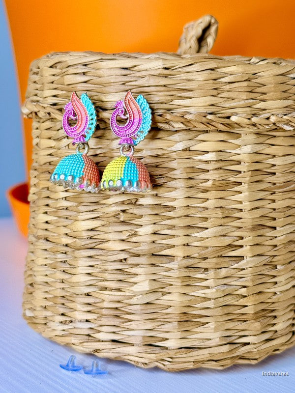 Colorful earrings on a woven basket with an orange background