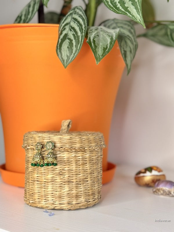 small golden green earrings hanging from a woven basket