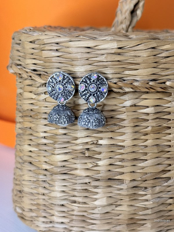 Silver earrings with gemstones on a woven basket against an orange background