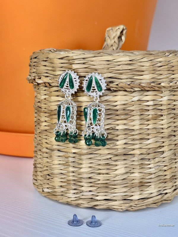 small green and silver earrings hanging from a woven basket