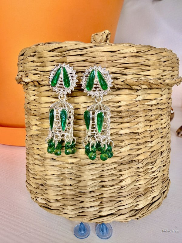 green and white small earrings hanging on a wicker basket