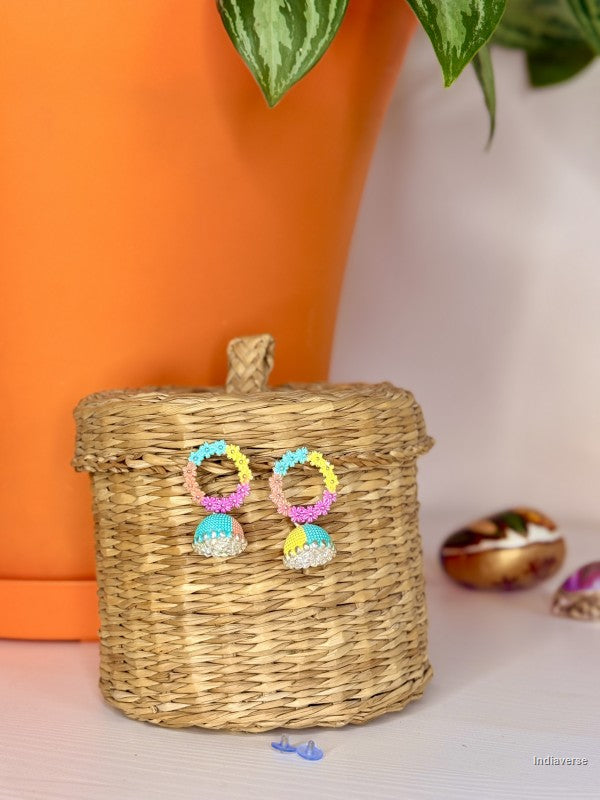 Colorful earrings on a woven box with an orange pot and plant in the background