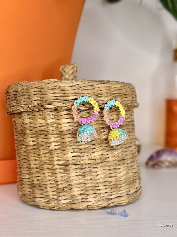 Colorful earrings on a woven basket with an orange and white background
