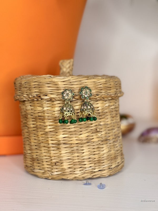 pair of golden and green small earrings hanging on a wicker basket
