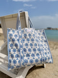 Blue and white patterned tote bag on a beach chair with ocean and sky in the background