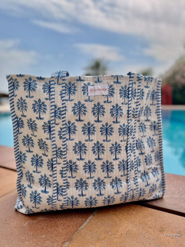 Fabric pouch with blue tree pattern on a wooden surface with a blurred outdoor background