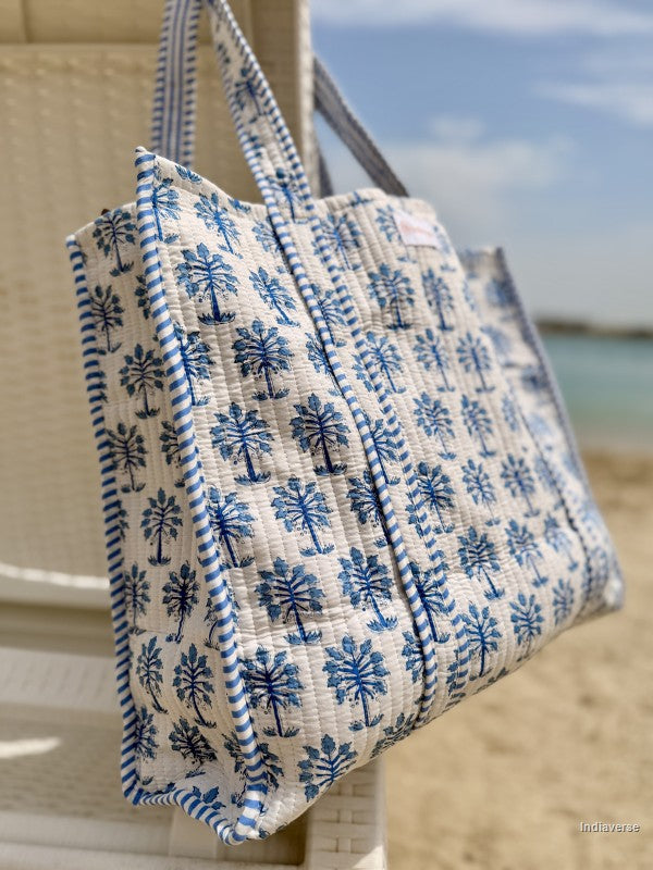 Blue and white patterned bag hanging on a wooden post by the beach