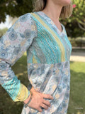 Person wearing a long-sleeve, patterned dress with a blurred outdoor background