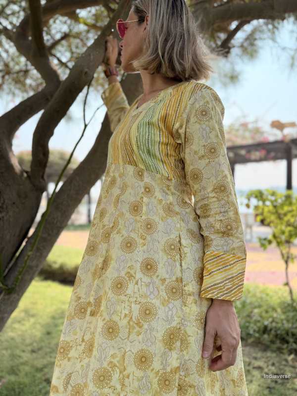 Woman wearing a yellow floral dress standing under a tree