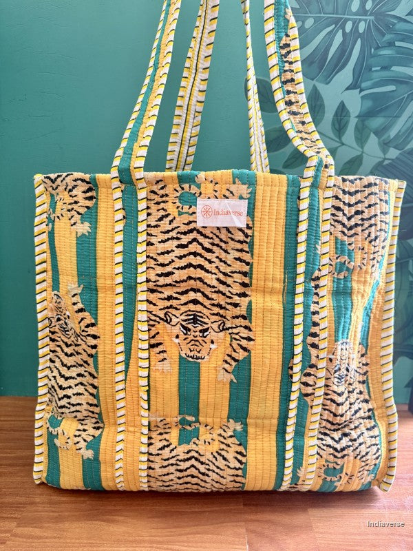 Tote bag with tiger pattern on a wooden surface against a green wall with leaf design.