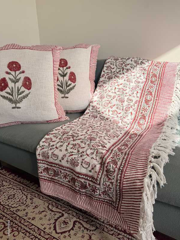 Decorative red and white patterned cotton throw with floral designs on a neutral background