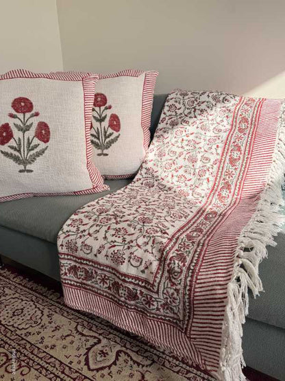 Decorative red and white patterned cotton throw with floral designs on a neutral background