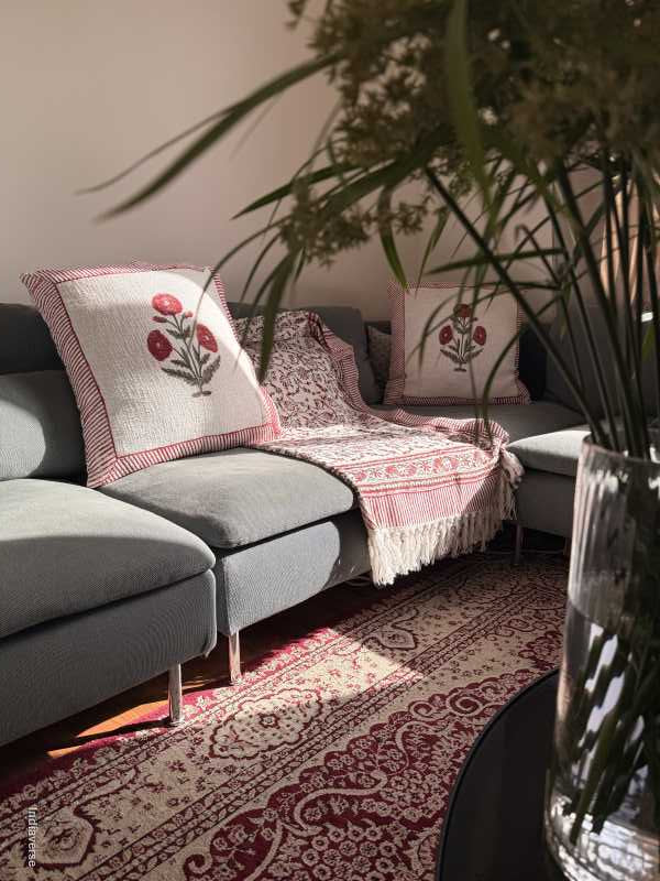 Decorative cushions and matching throw with floral patterns on a sofa next to a patterned rug.
