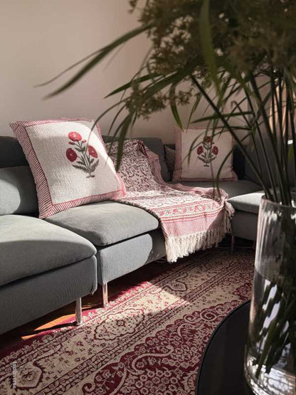 Decorative cushions and matching throw with floral patterns on a sofa next to a patterned rug.