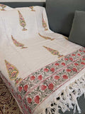 White fabric with intricate floral patterns and red accents on a dark background