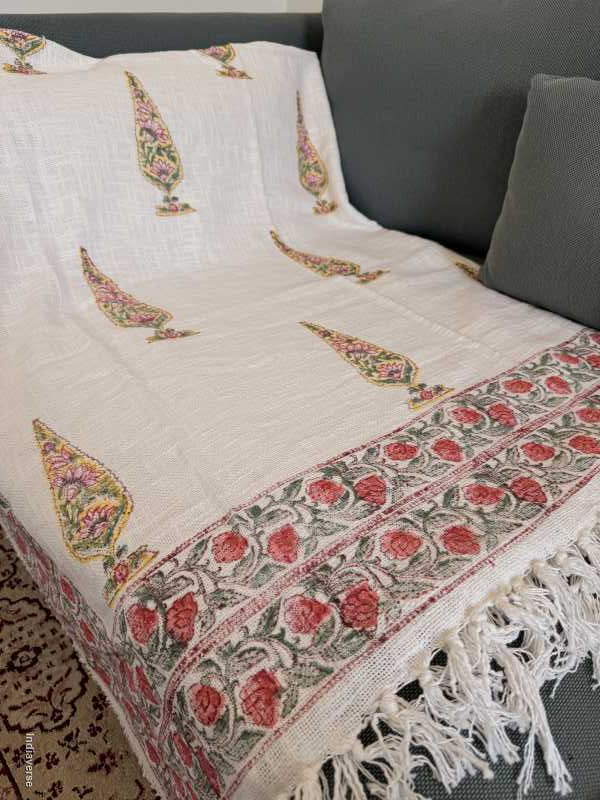 White fabric with intricate floral patterns and red accents on a dark background