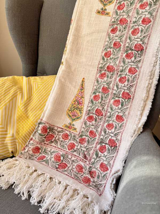 Decorative scarf with floral patterns and tassels on a mannequin against a neutral background.