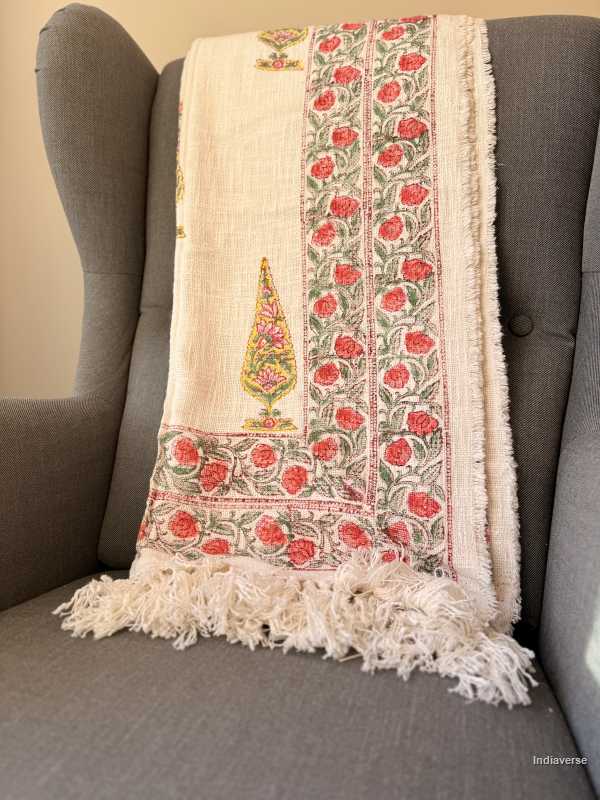 Decorative blanket with floral patterns draped over a gray armchair.