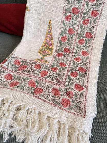 Decorative fabric with floral patterns and fringes on a plain background