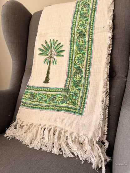 Decorative blanket with palm tree design draped over a gray chair