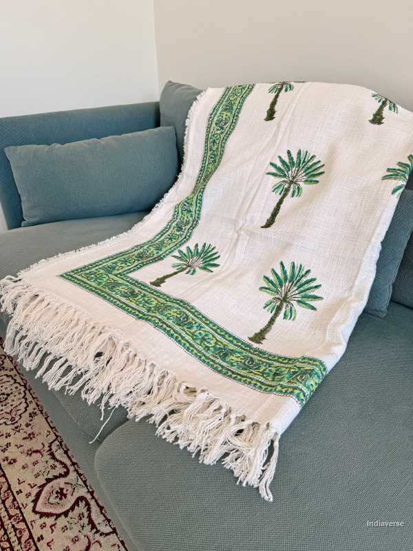 Decorative throw blanket with palm tree design on a gray sofa.