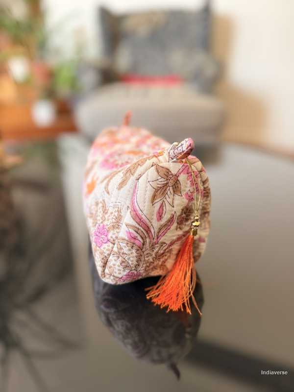 Decorative fabric pouch with floral patterns and orange tassel on a blurred background | Paradise