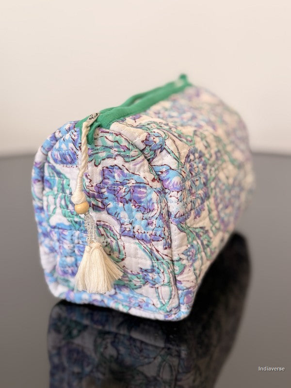 toiletry pouch with white tassel sitting on a glass surface