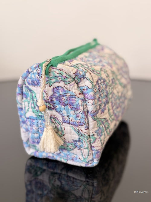 toiletry pouch with white tassel sitting on a glass surface