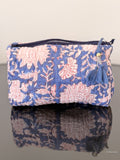 blue toiletry pouch with white flowers sitting on a glass surface