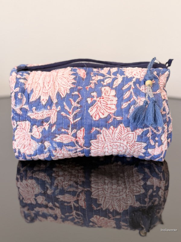 blue toiletry pouch with white flowers sitting on a glass surface