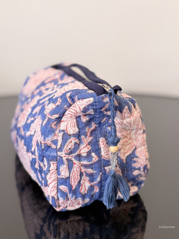 Blue and pink floral patterned bag with a tassel on a neutral background