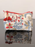 toiletry bag with floral design and red tassel sitting on a glass surface