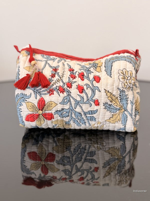 toiletry bag with floral design and red tassel sitting on a glass surface