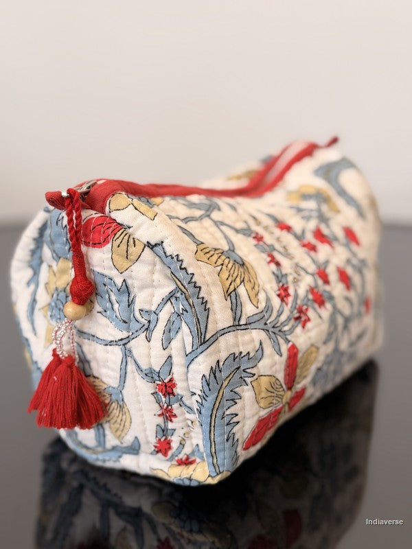 Decorative pouch with floral patterns and red accents on a reflective surface.