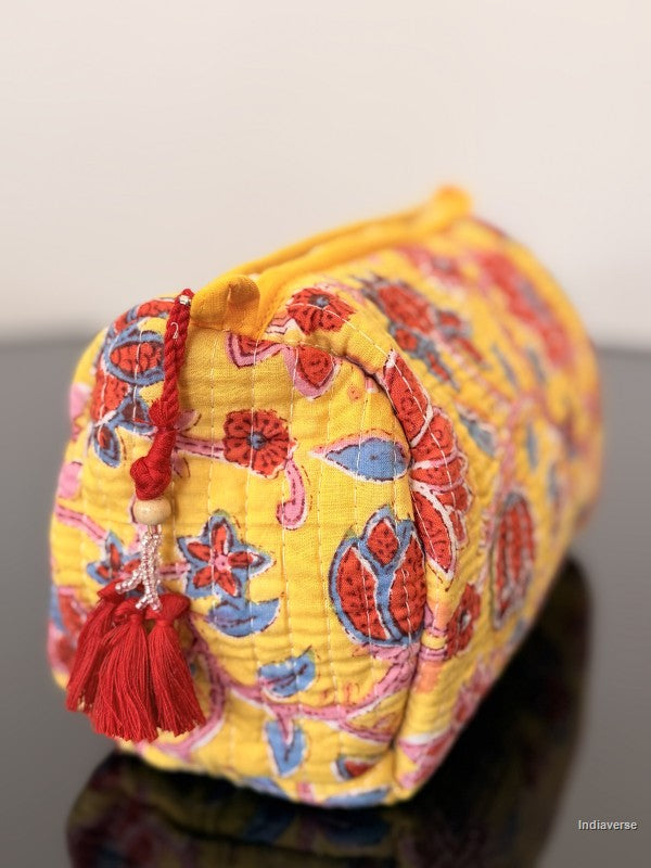 floral toiletry bag with red tassels sitting on a glass surface