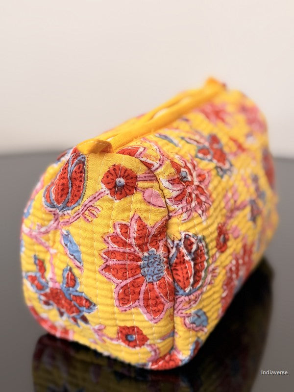 red flowers and yellow toiletry bag sitting on a glass surface