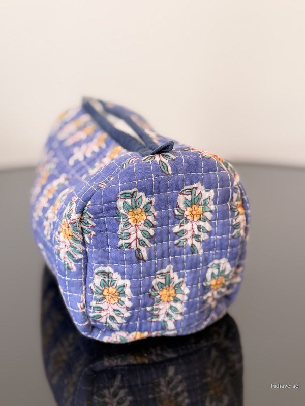 Blue floral-patterned bag on a reflective surface with a white background