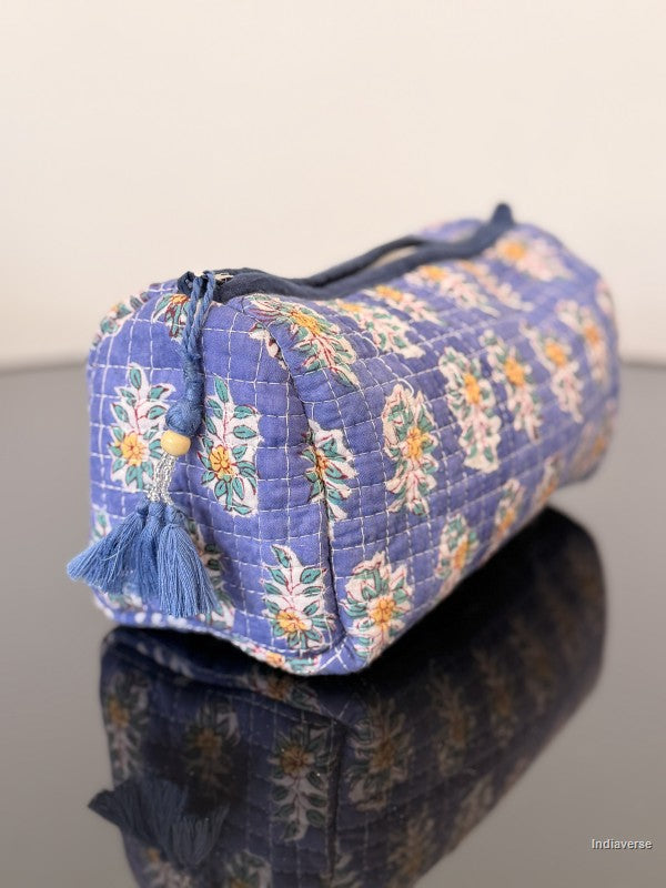 Blue floral-patterned cosmetic bag on a reflective surface with a white background
