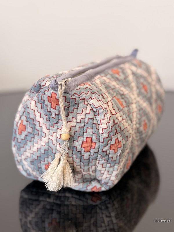 blue toiletry pouch with geometric pattern sitting on a glass surface