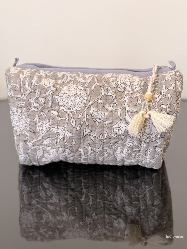 Floral embroidered pouch with tassels on a gray background