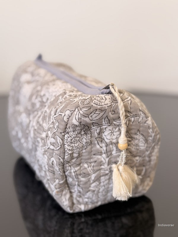 Floral-patterned pouch with a tassel on a reflective surface