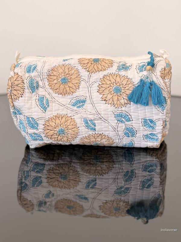 orange floral toiletry bag with blue tassels sitting on a glass surface