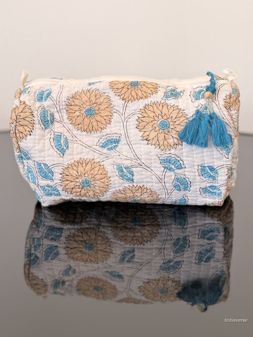 orange floral toiletry bag with blue tassels sitting on a glass surface