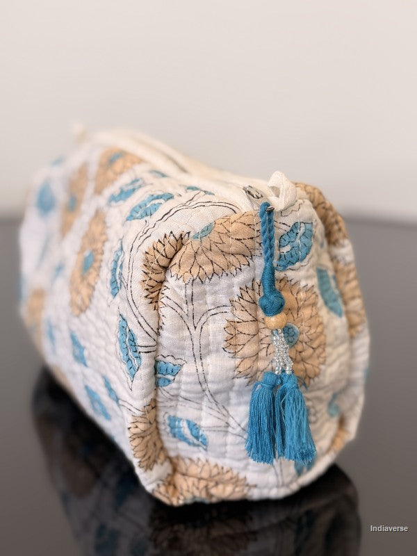 pouch with blue tassels and floral design sitting on a glass surface