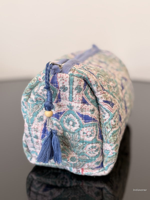Decorative fabric pouch with tassels on a neutral background