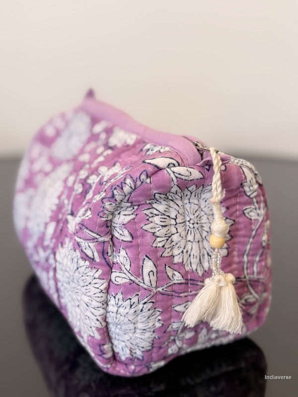 purple toiletry bag with white flowers sitting on a glass surface
