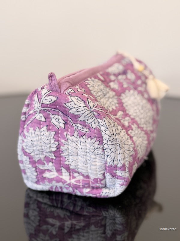 Purple cosmetic bag with white floral pattern on a reflective surface