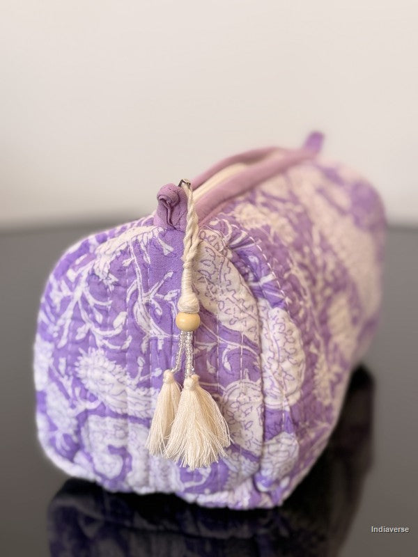 Purple decorative pillow with floral patterns and tassels on a plain background
