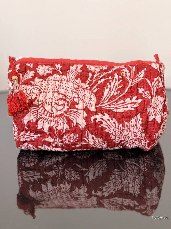 red toiletry bag with floral pattern sitting on a glass surface